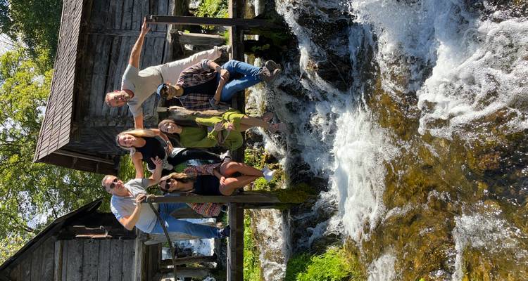 Groupe de personnes posant près d'un ruisseau avec des maisons en bois.