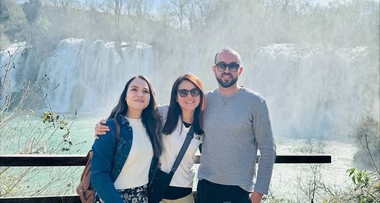 Trois personnes posent devant une grande cascade.
