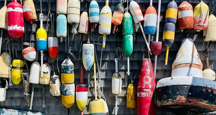 Collection colorée de bouées de pêche usées par les intempéries accrochées à un mur à bardeaux dans une ville côtière de la Nouvelle-Angleterre.