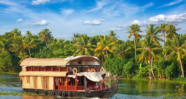 Traditional houseboat cruising on a river surrounded by greenery.