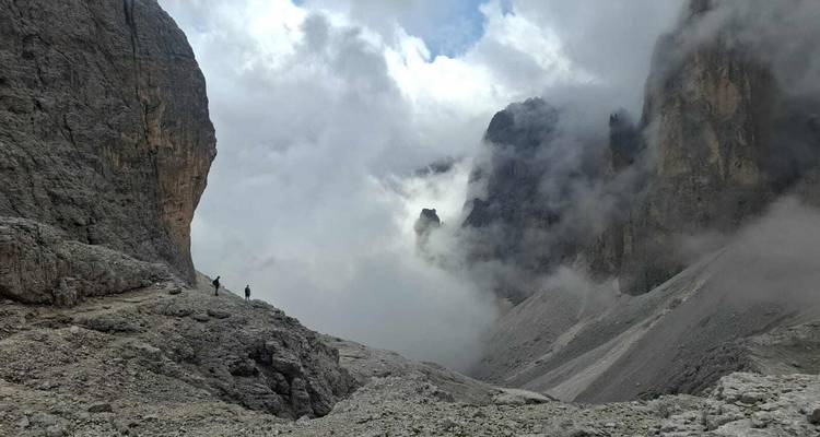 Wolken die door een steile rotsachtige vallei rollen tussen torenhoge Dolomietenrotswanden