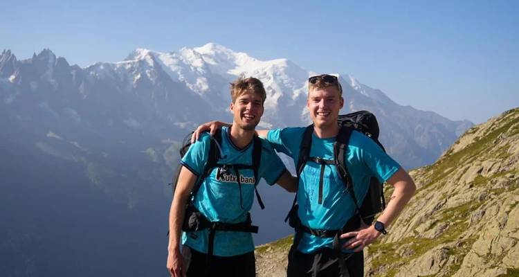 Deux amis en chemises assorties souriant les bras autour l'un de l'autre en haute altitude dans les Alpes