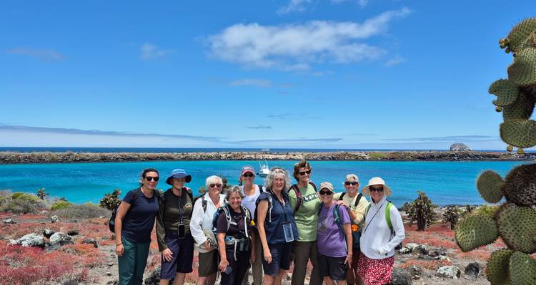 Un groupe de personnes posant sur un rivage rocheux avec de l'eau turquoise.
