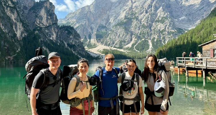 Groupe de randonneurs posant près d'un lac alpin aux eaux cristallines entouré de falaises imposantes