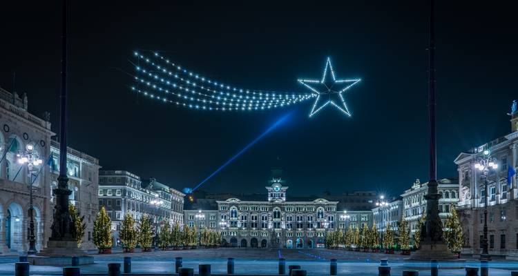 Piazza Unità d'Italia 's nachts met geanimeerde vallende sterren lichtinstallatie en kerstbomen langs het plein.