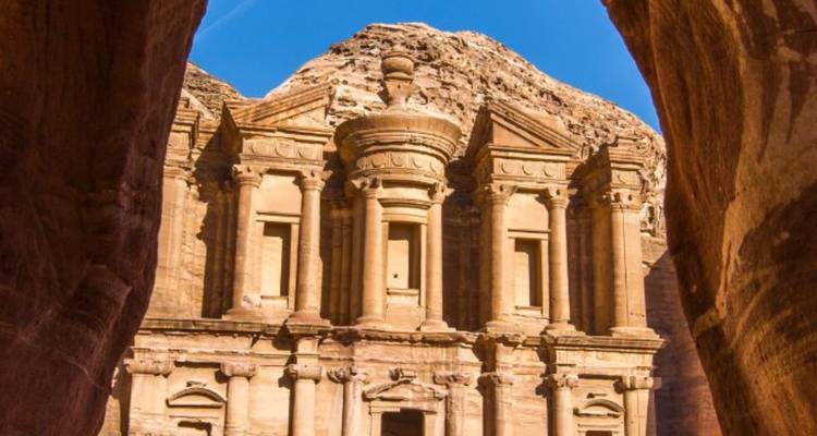 Majestueus Klooster van Petra omlijst door ruige zandstenen muren onder een heldere blauwe hemel.