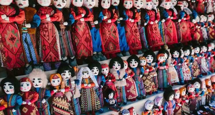 Muro de muñecas georgianas artesanales coloridas vestidas con textiles tradicionales en venta en un mercado.