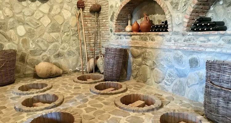 Bodega tradicional georgiana con tinajas de barro qvevri circulares empotradas en el suelo de piedra.