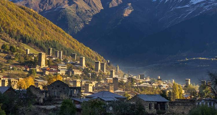 Pueblo montañoso de Mestia salpicado de torres medievales svan entre bosques otoñales y picos nevados.