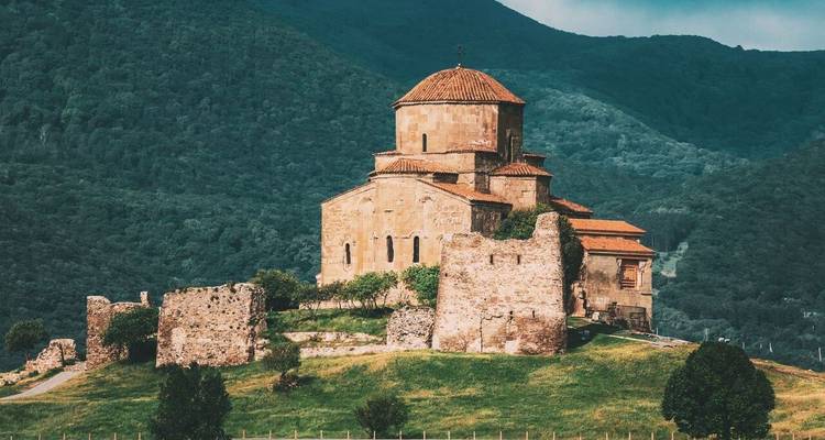 Histórico Monasterio Jvari encaramado en una colina verde con vistas a valles confluentes.