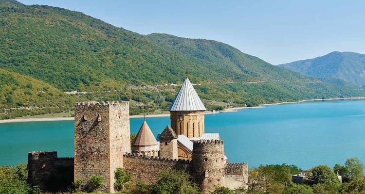 Complejo de fortaleza de Ananuri con vista al turquesa Embalse de Aragvi y colinas boscosas.