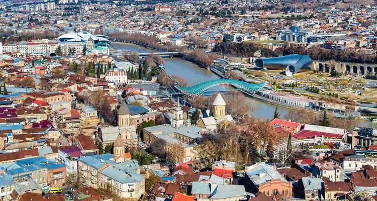 Panorama aérea de Tiflis con el río Kura, el Puente de la Paz y el horizonte de la ciudad.