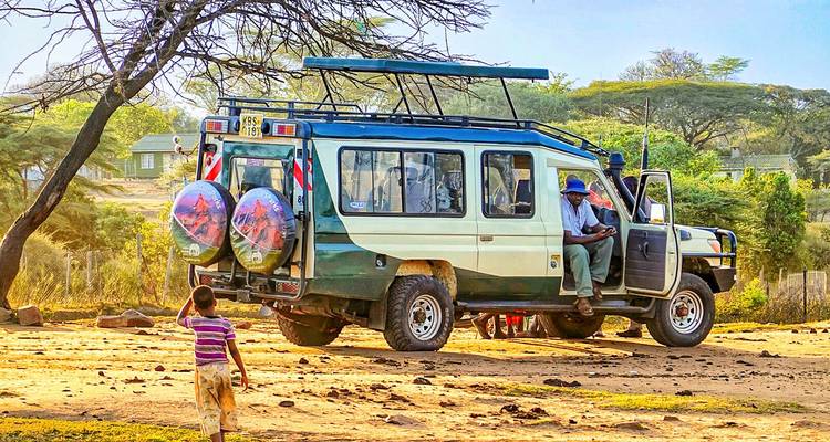 Ein Safari-Fahrzeug mit Menschen und einem Kind in einer Savanne.