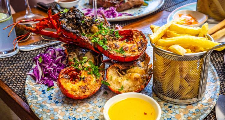 Festin de fruits de mer dressé avec homard grillé, frites et salades colorées dans un cadre de restaurant