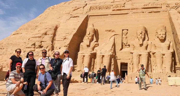 Tour group in front of a vast ancient temple with carved statues.