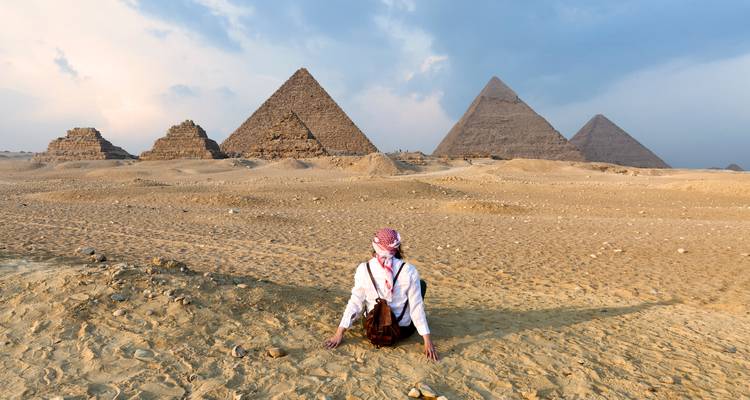 Viajeros disfrutando de una vista del desierto de las pirámides con nubes dramáticas.