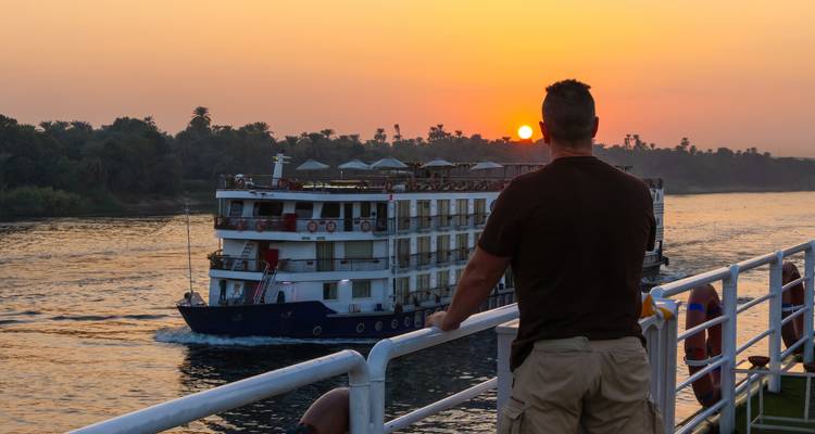 Crucero en el río Nilo durante la puesta del sol con una persona observando.