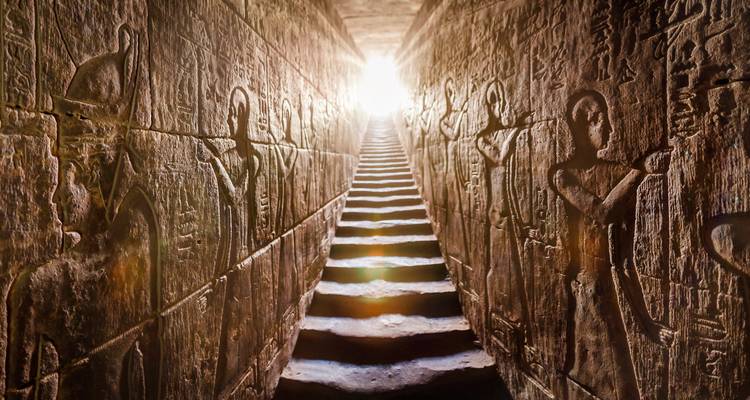 Escalera dramática que conduce hacia arriba con tallados antiguos en las paredes.