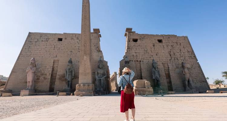Individuo capturando una foto frente al Templo de Luxor bajo un cielo despejado.