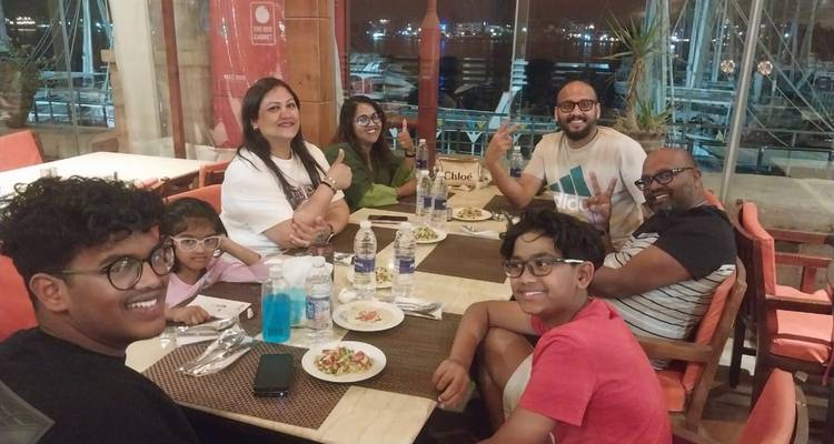 Famille souriante assise autour d'une table de restaurant au bord de la marina pendant le dîner.