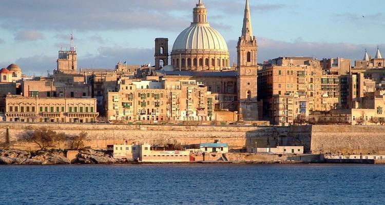 Historische Stadtsilhouette mit Kuppelkathedrale und Wasser.