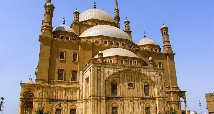 Une grande mosquée avec plusieurs dômes et minarets sous un ciel dégagé.