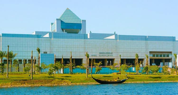 Un bâtiment moderne avec un toit en forme de pyramide au bord d'un lac.