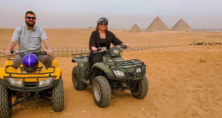 Un couple sur des VTT traversant un paysage désertique avec des pyramides.