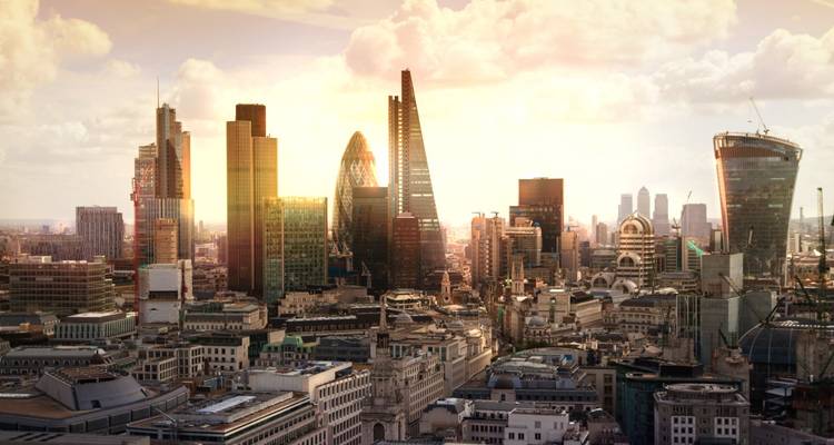 Modern skyline of London’s financial district at golden sunset with the Gherkin and Shard prominent.