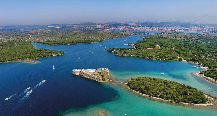 Vue aérienne de baies bleues scintillantes et d'îles boisées près de Šibenik avec un fort maritime historique.