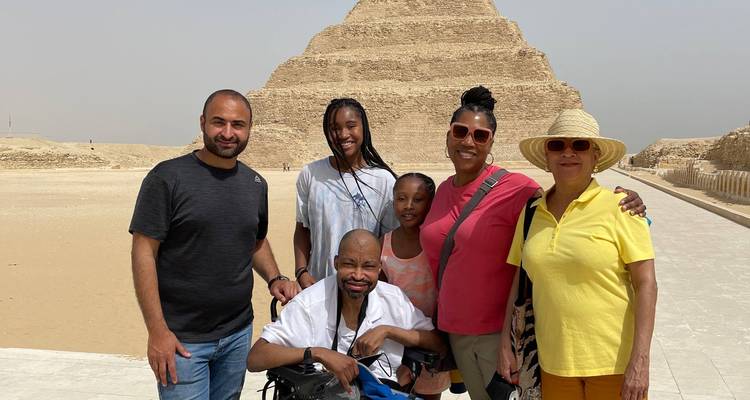 Groupe de voyageurs souriant devant la pyramide à degrés de Djéser à Saqqarah.