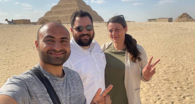Selfie de trois voyageurs faisant le signe de la paix avec la pyramide à degrés en arrière-plan.