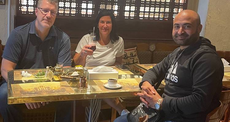 Trois voyageurs assis à une table de café traditionnel du Caire savourant des boissons.