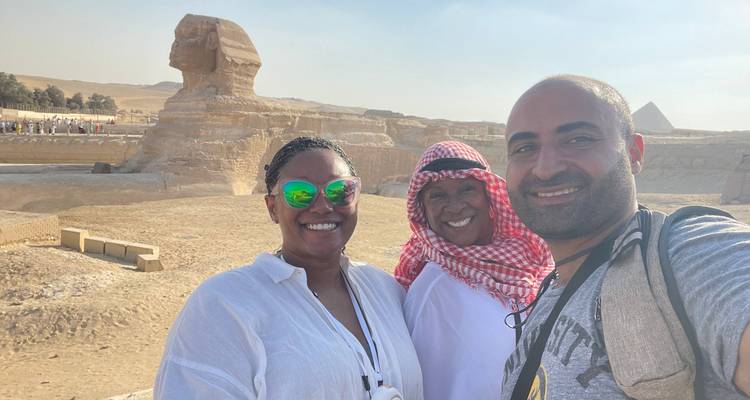 Selfie avec trois voyageurs souriants devant le Sphinx sous la lumière de l'après-midi.