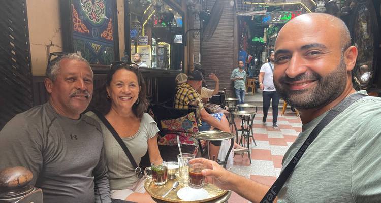 Trois voyageurs se détendent avec du thé traditionnel dans un café du Caire à l'atmosphère chaleureuse et au décor coloré.