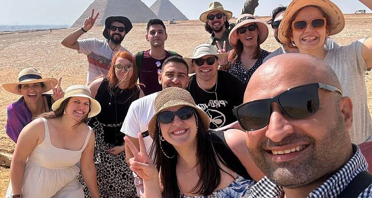 Grand selfie de groupe de voyageurs enthousiastes avec les pyramides de Gizeh qui se dressent en arrière-plan.