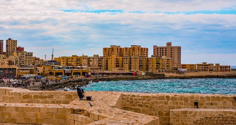 Paysage urbain côtier avec des immeubles d'appartements modernes bordant une baie méditerranéenne turquoise.