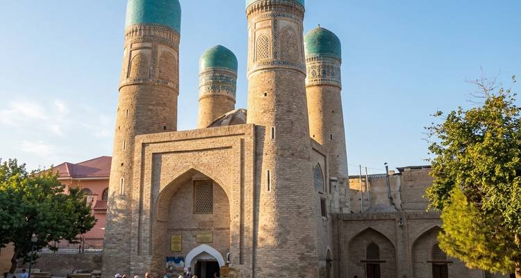 Las cuatro cúpulas turquesas de Chor Minor se alzan sobre la entrada de ladrillo bajo la suave luz del atardecer.