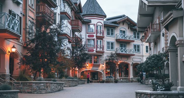 Charming pedestrian street flanked by alpine-style buildings with warm evening lights and a strolling couple.