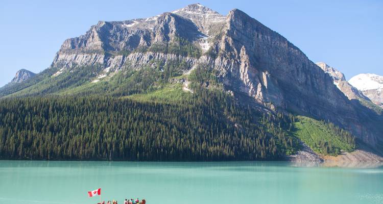 Canoe of visitors on the milky-turquoise waters of Lake Louise beneath towering alpine peaks.