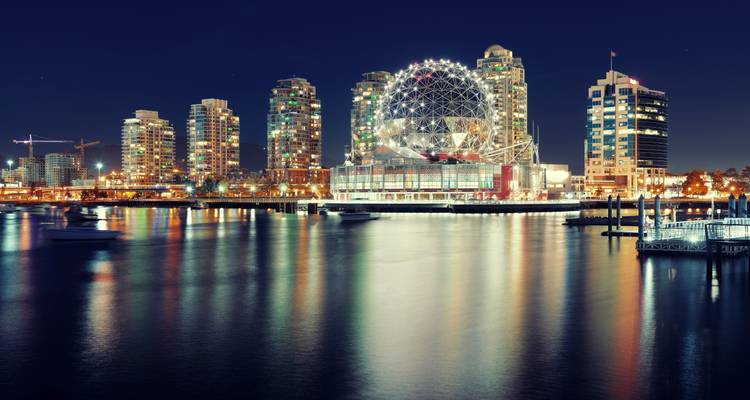 Night skyline of Vancouver featuring the illuminated geodesic Science World reflecting on calm harbor waters