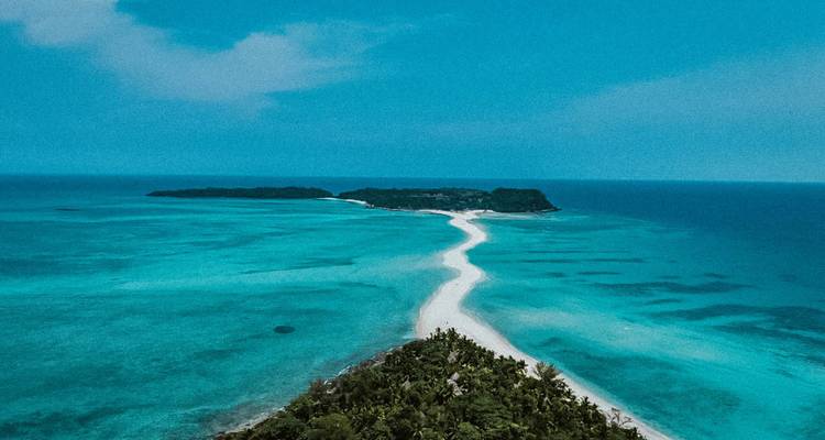 Vue aérienne d'une mer turquoise avec un banc de sable blanc reliant deux îles verdoyantes luxuriantes à Madagascar.