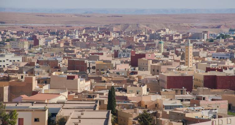 Vista expansiva sobre un pueblo desértico con edificios de techos planos que se extienden hacia un horizonte árido.