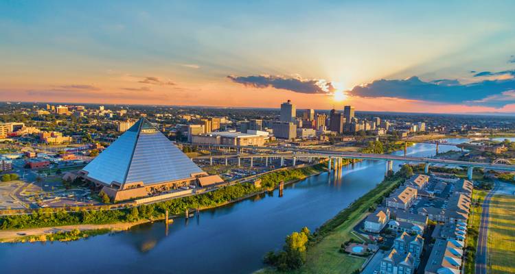 Luchtfoto bij zonsondergang van de skyline van Memphis met glazen piramidevormige arena naast de rivier.