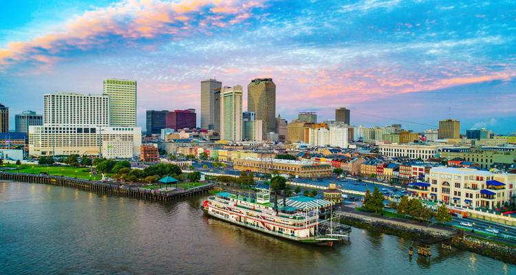 Stoomboot op de Mississippi rivier met kleurrijke New Orleans skyline onder dramatische dageraadwolken.