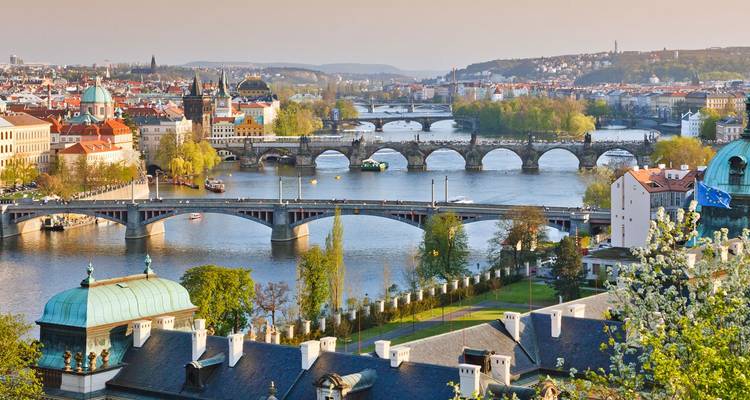 Vista panorámica de los puentes de Praga arqueándose sobre el río Vltava al atardecer brumoso.