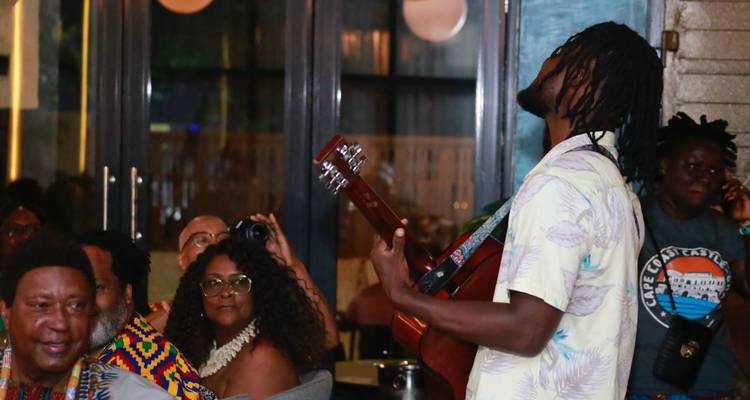 Divertissement en soirée avec un guitariste se produisant pour des convives assis dans un restaurant tamisé.