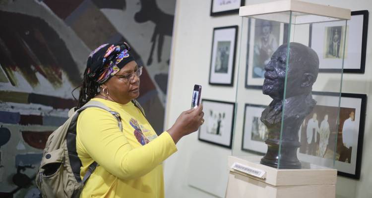 Un visiteur photographie un buste en bronze exposé dans une vitrine d'un musée d'histoire.