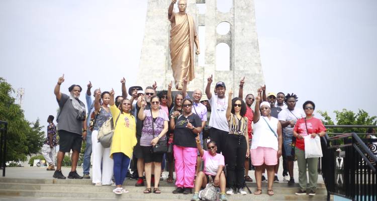 Un grand groupe de touristes pose avec enthousiasme devant la statue de Kwame Nkrumah à Independence Square.