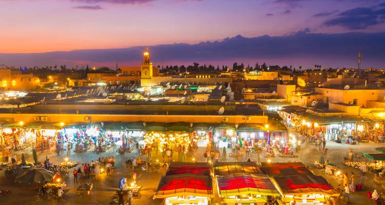 Evening view over Jemaa el-Fnaa square illuminated by countless market stalls and lanterns.